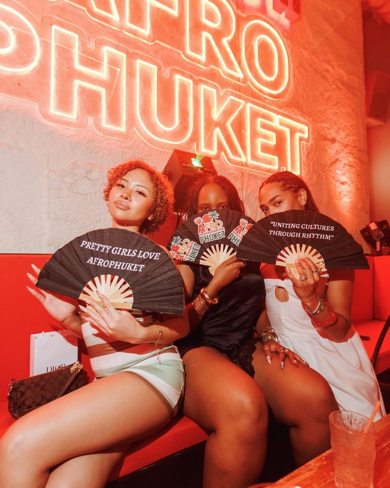 Guests with Afro Phuket fans under the neon sign
